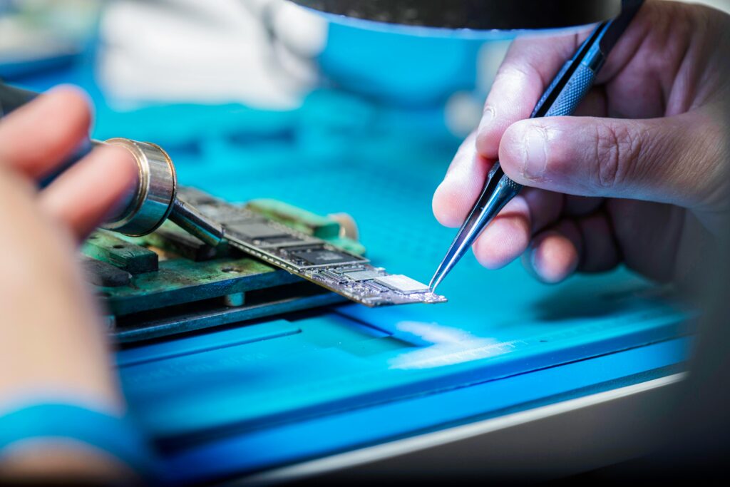 Hands delicately holding tools repairing a circuit board with precision.